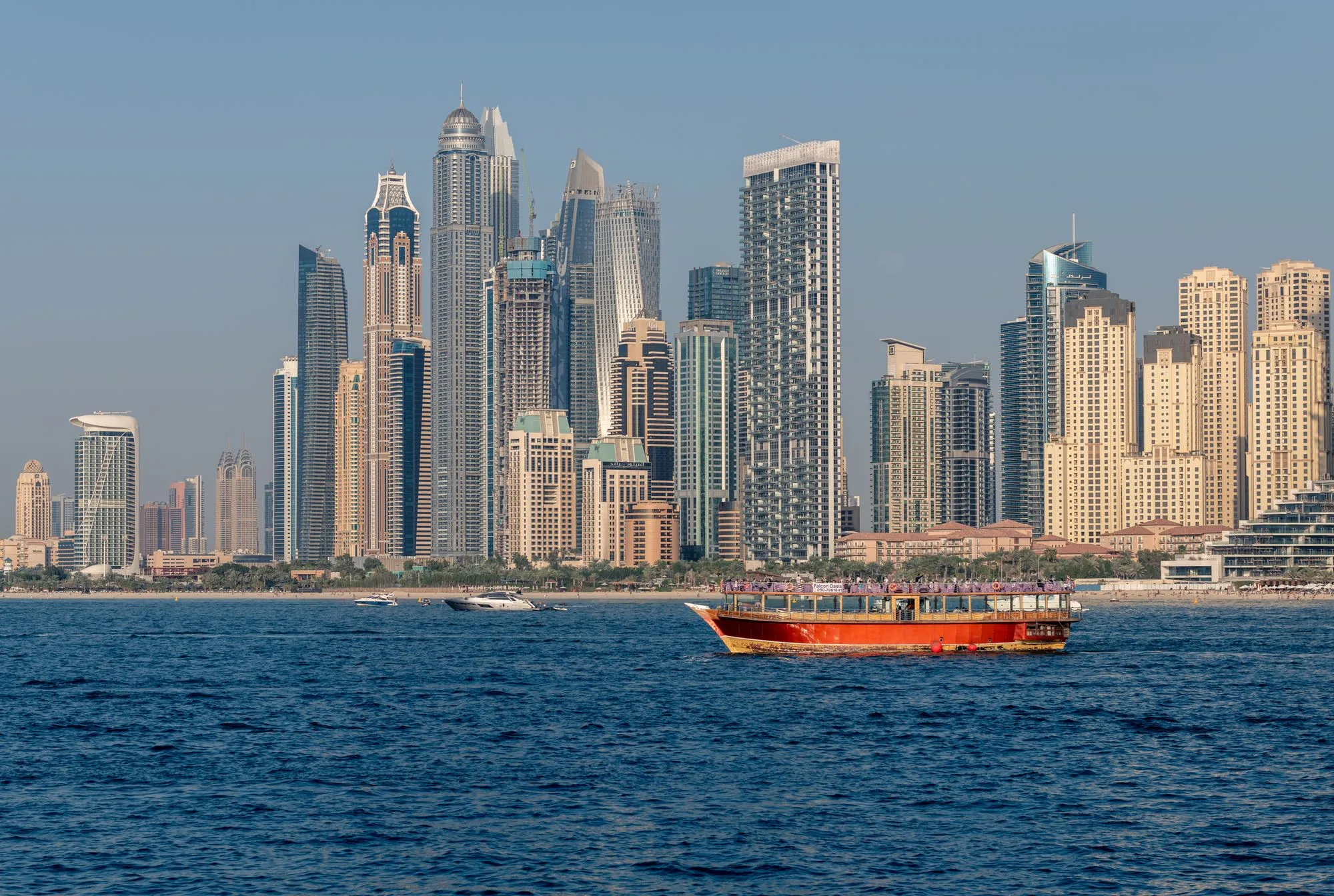 A traditional wooden dhow cruising on the Arabian Gulf in front of the Dubai Marina skyline