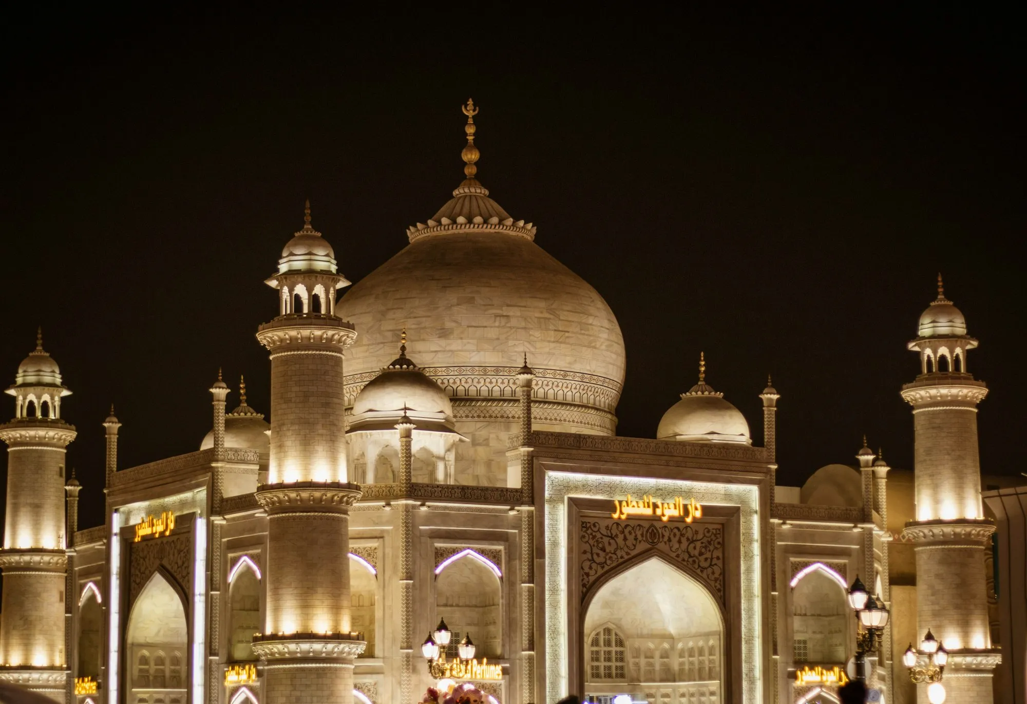Illuminated domed pavilion with minarets at Global Village Dubai at night